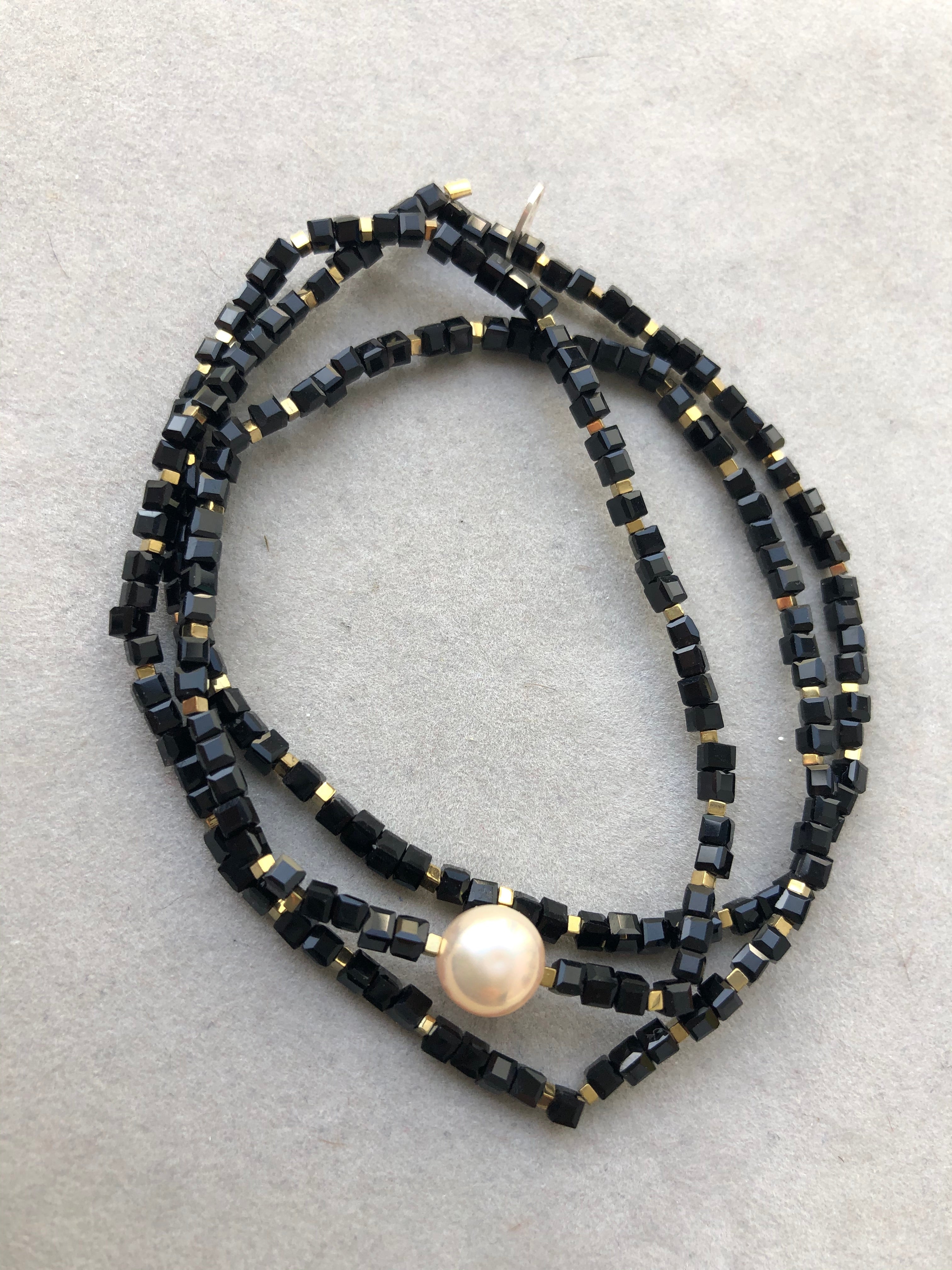 Goldfarbene Hämatitwürfel, schwarze Glasperlen und eine Süßwasserperle