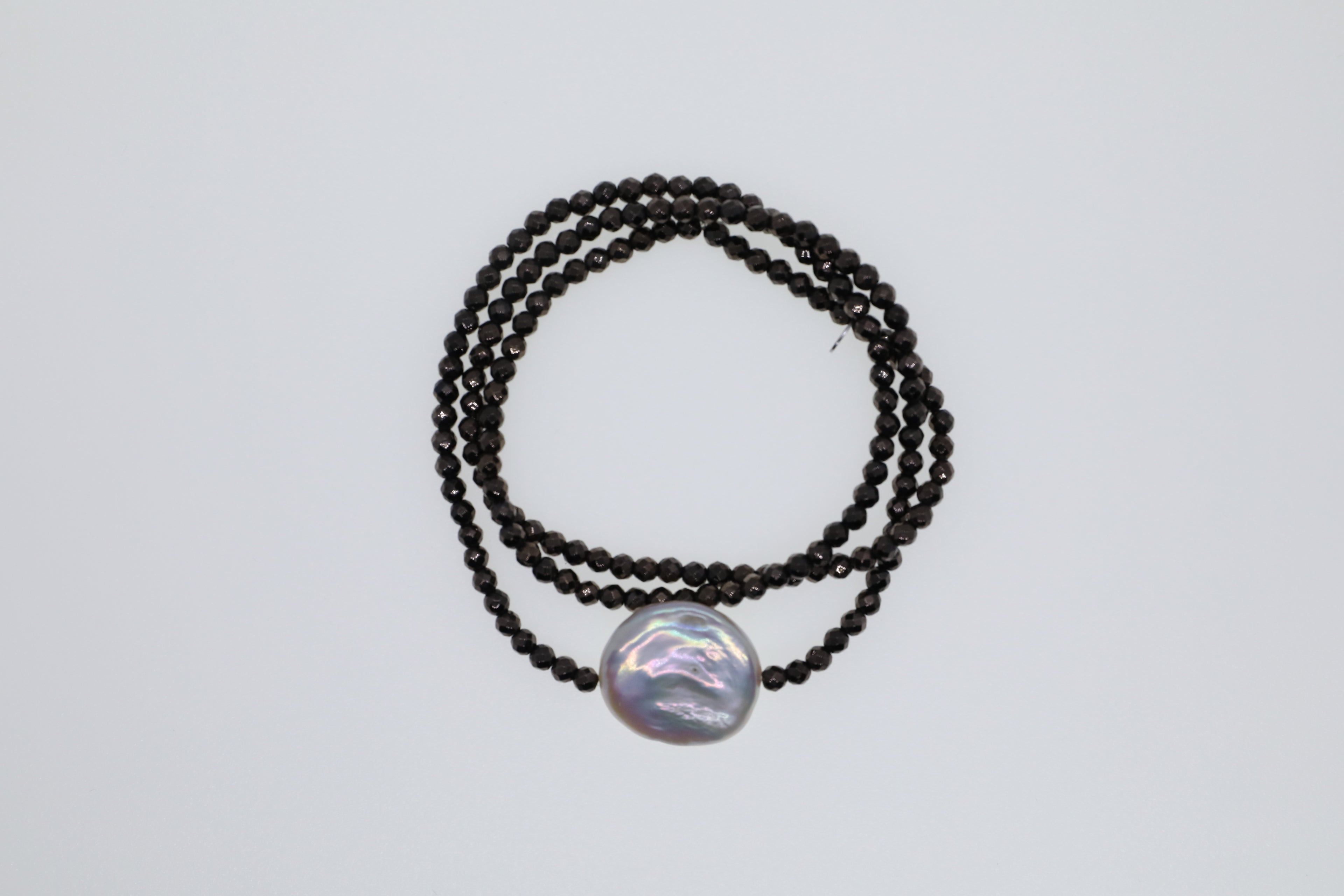 Dunkelbraune Hämatite und eine weiße, flache Süßwasserperle