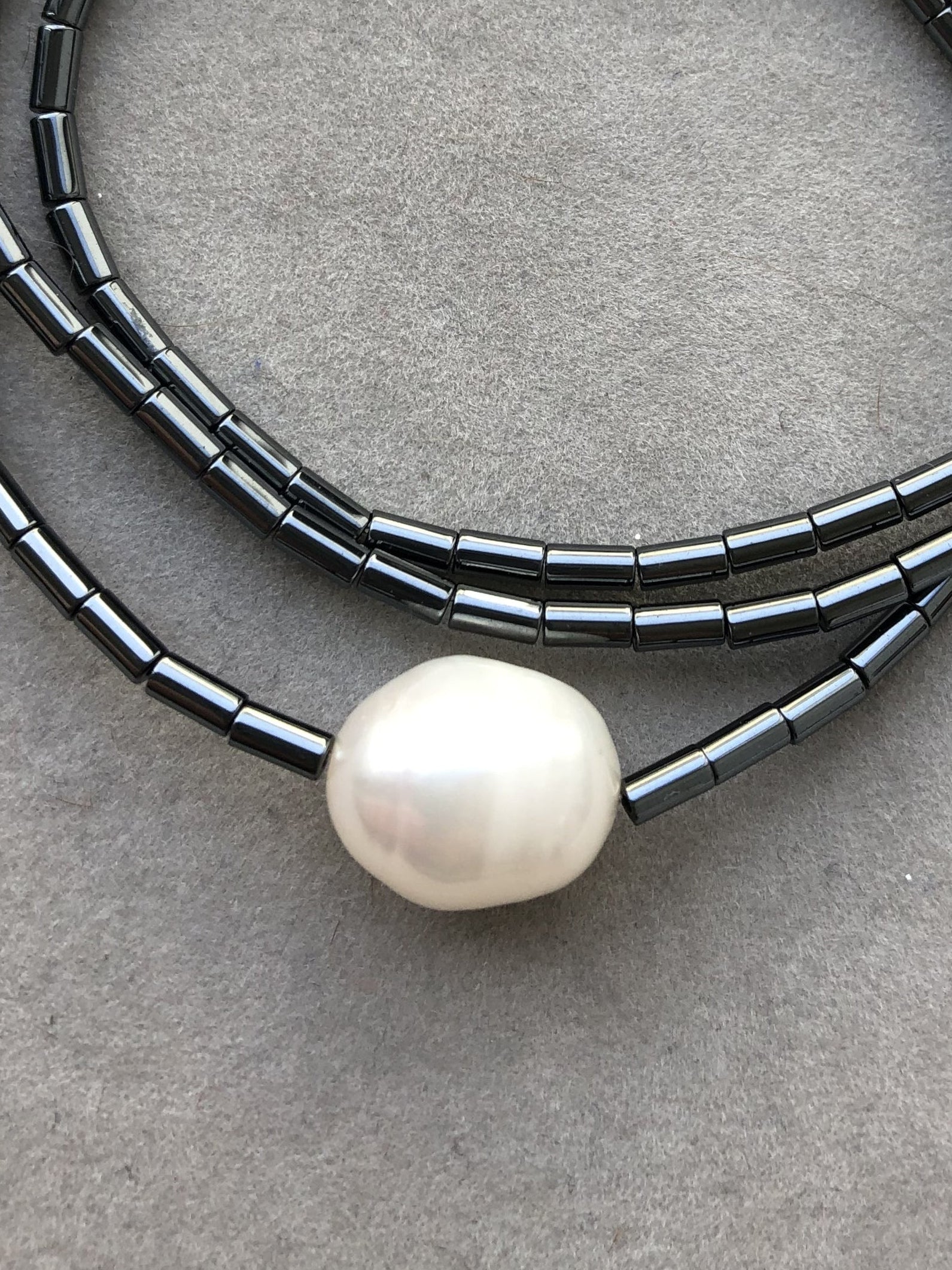 Weiße Süßwasserperle zusammen mit anthrazitfarbenem Hämatit