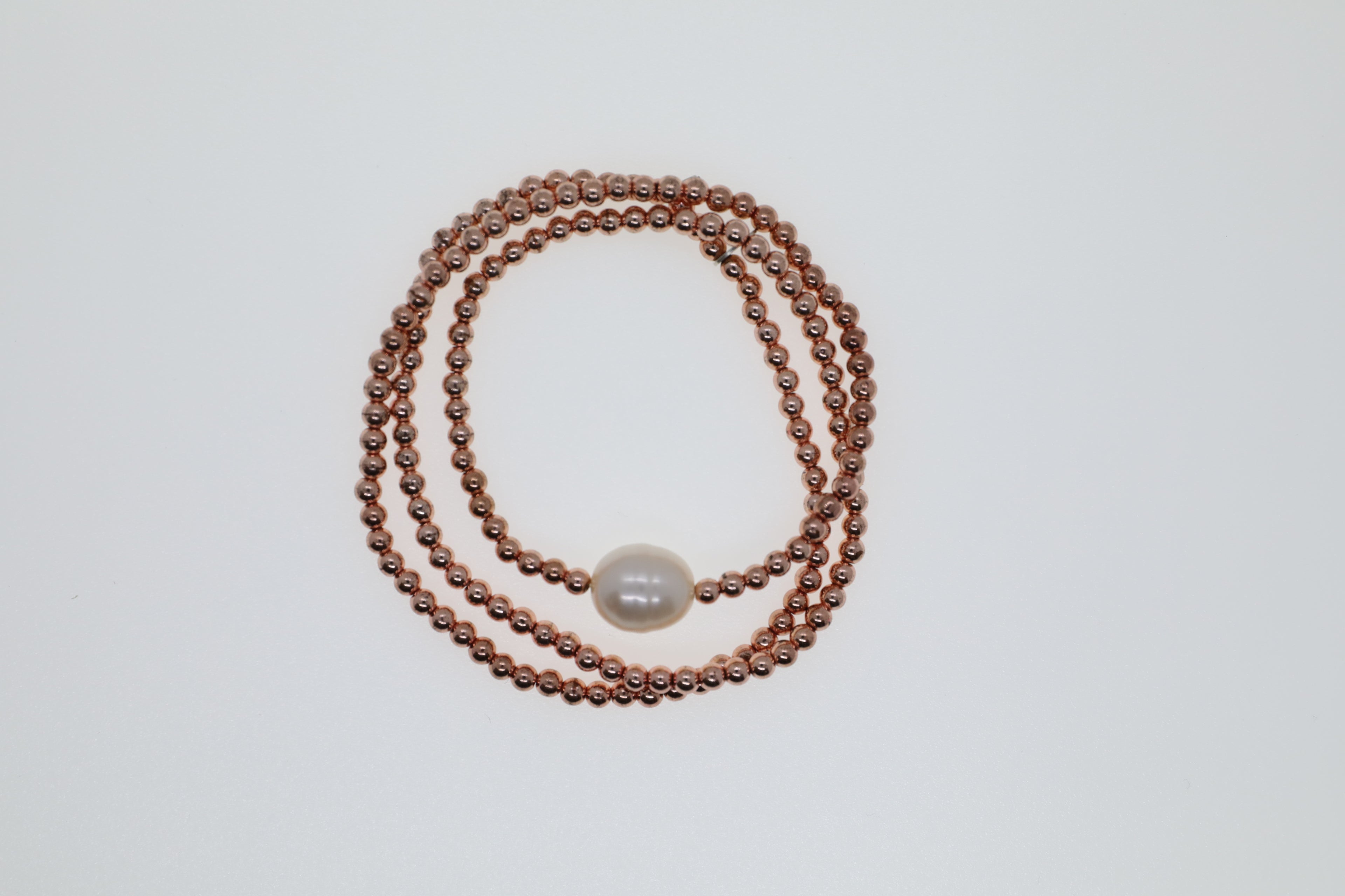 Kupferfarbene Hämatitkugeln und eine weiße Süßwasserperle