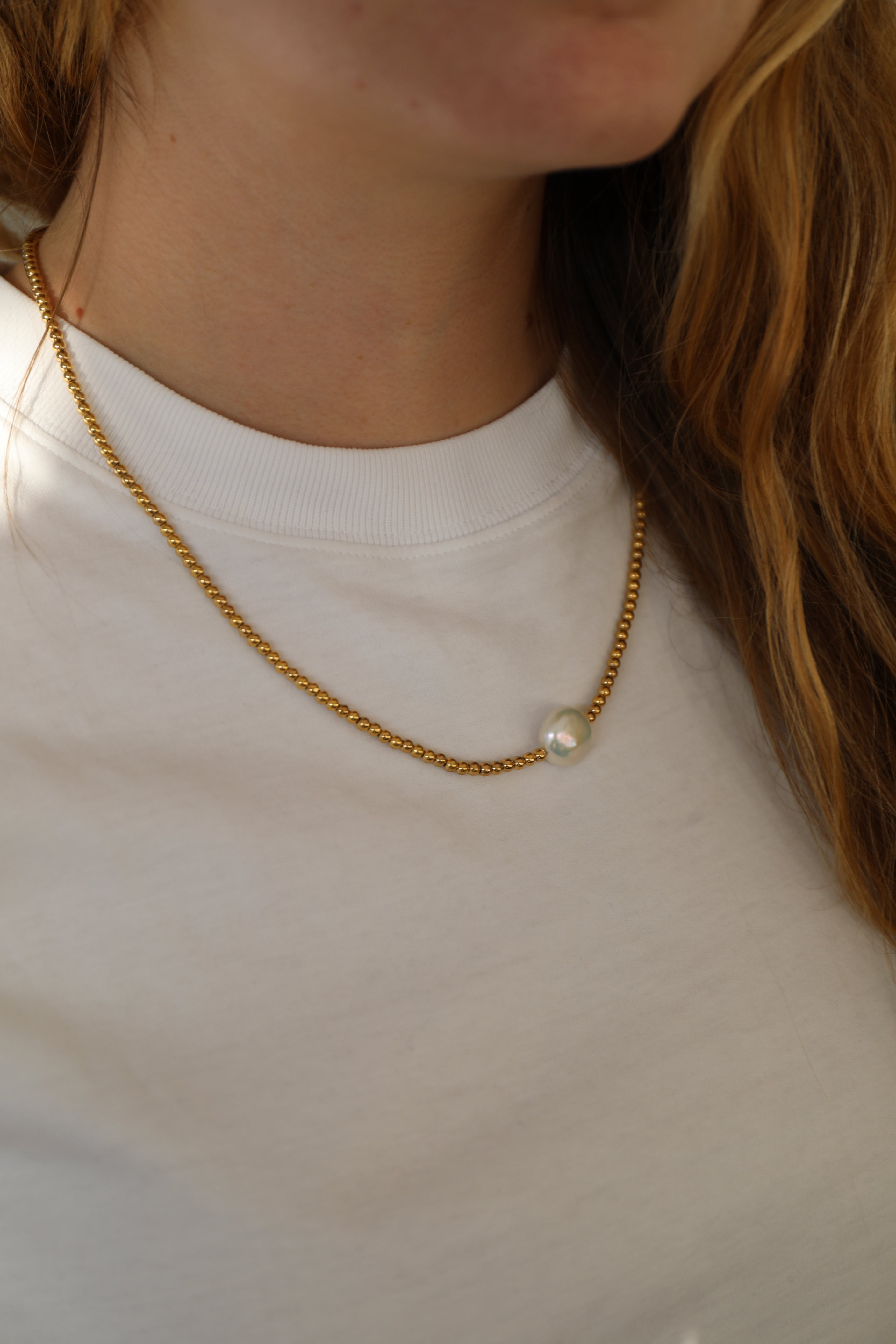 Goldfarbene Hämtitkugeln und eine große, weiße Süßwasserperle