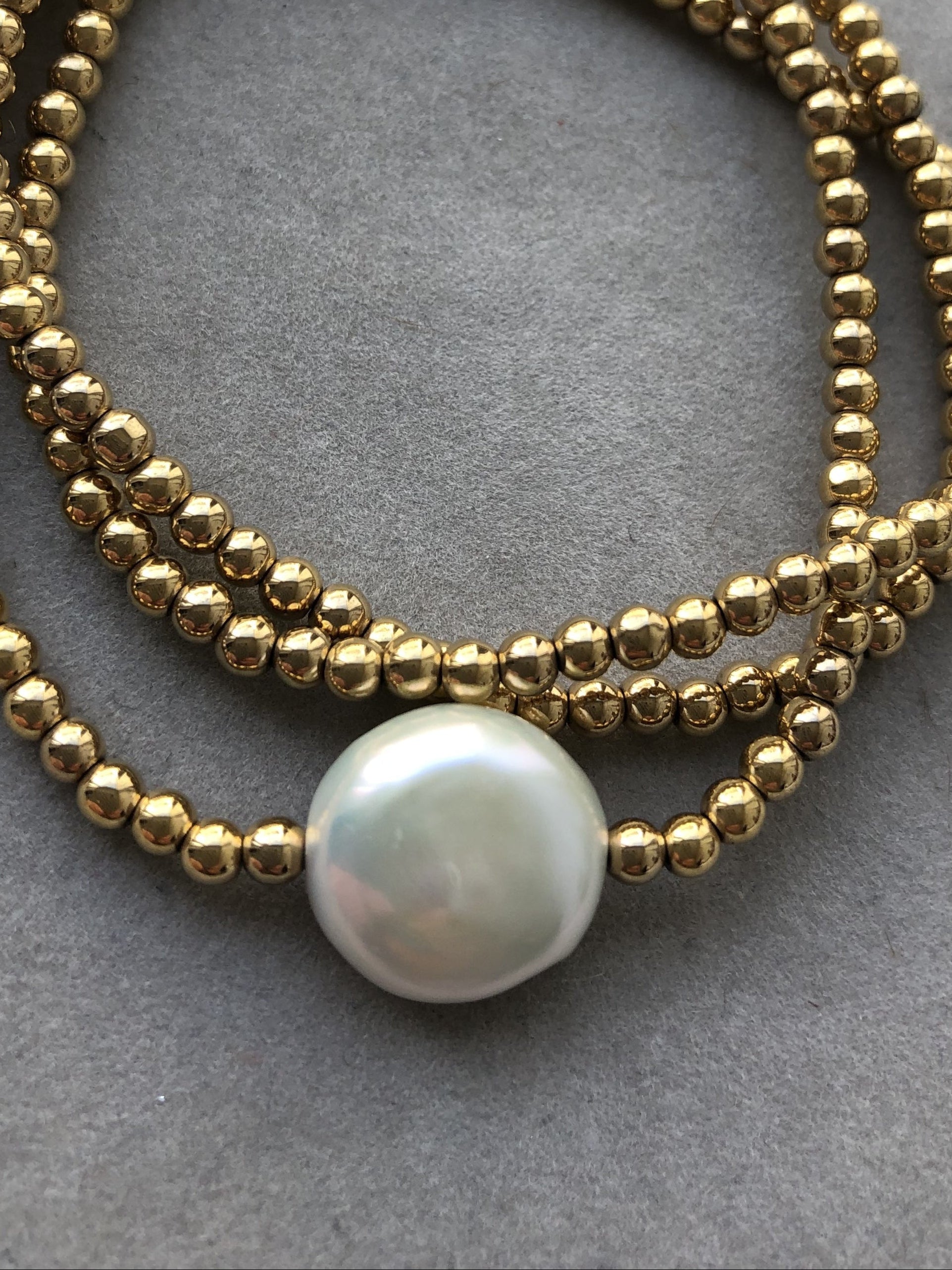 Goldfarbene Hämtitkugeln und eine große, weiße Süßwasserperle