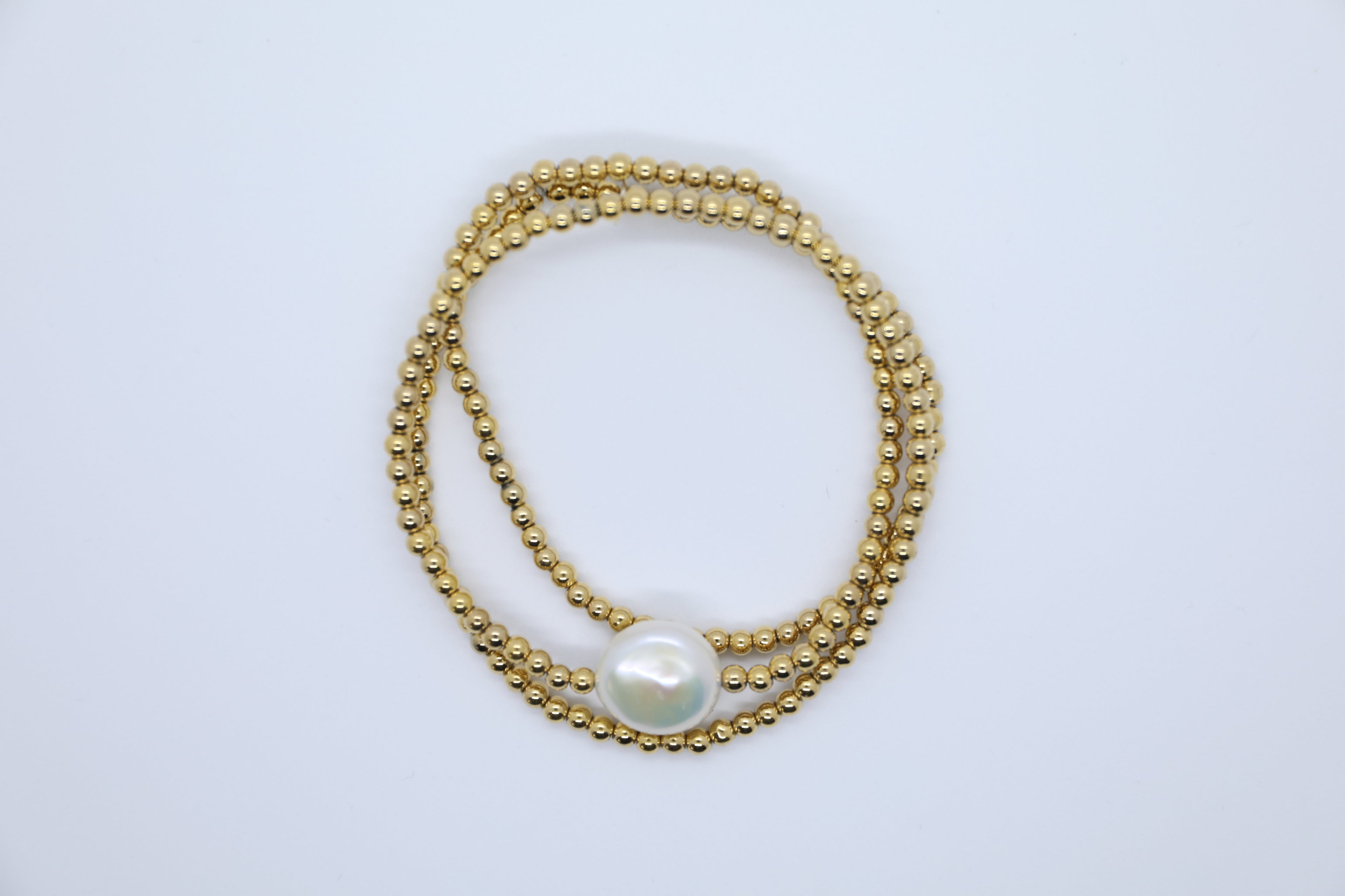 Goldfarbene Hämtitkugeln und eine große, weiße Süßwasserperle