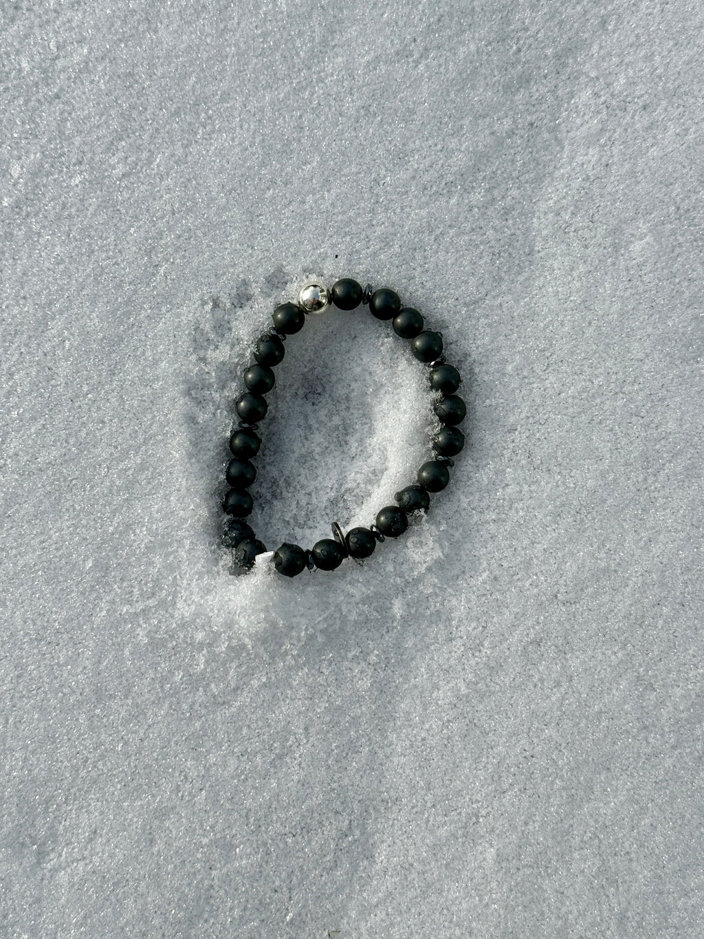 Anthrazitfarbene Hämatitkugeln und glänzende Silberkugel