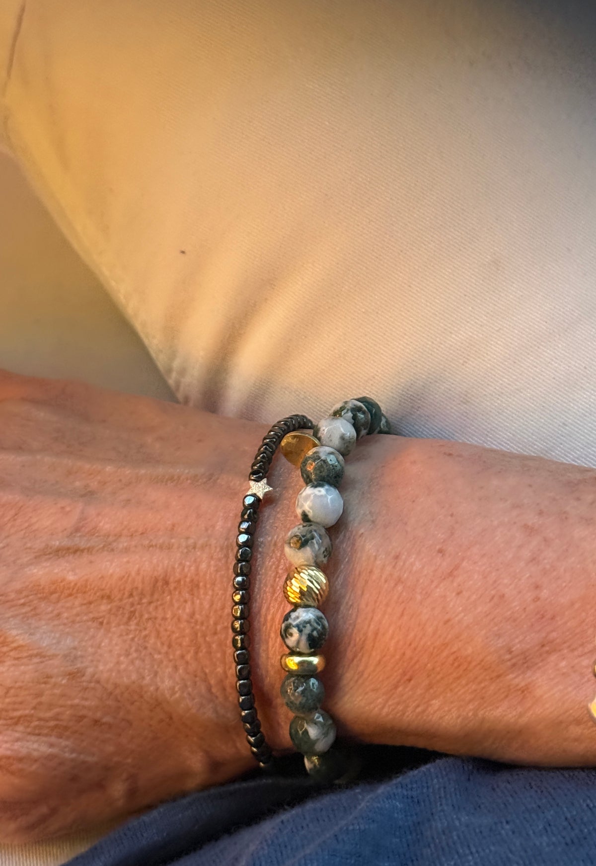 Armband aus anthrazitfarbenen Hämatitwürfeln und einem vergoldeten Stern aus Silber. Dazu eine vergoldete Silberkugel