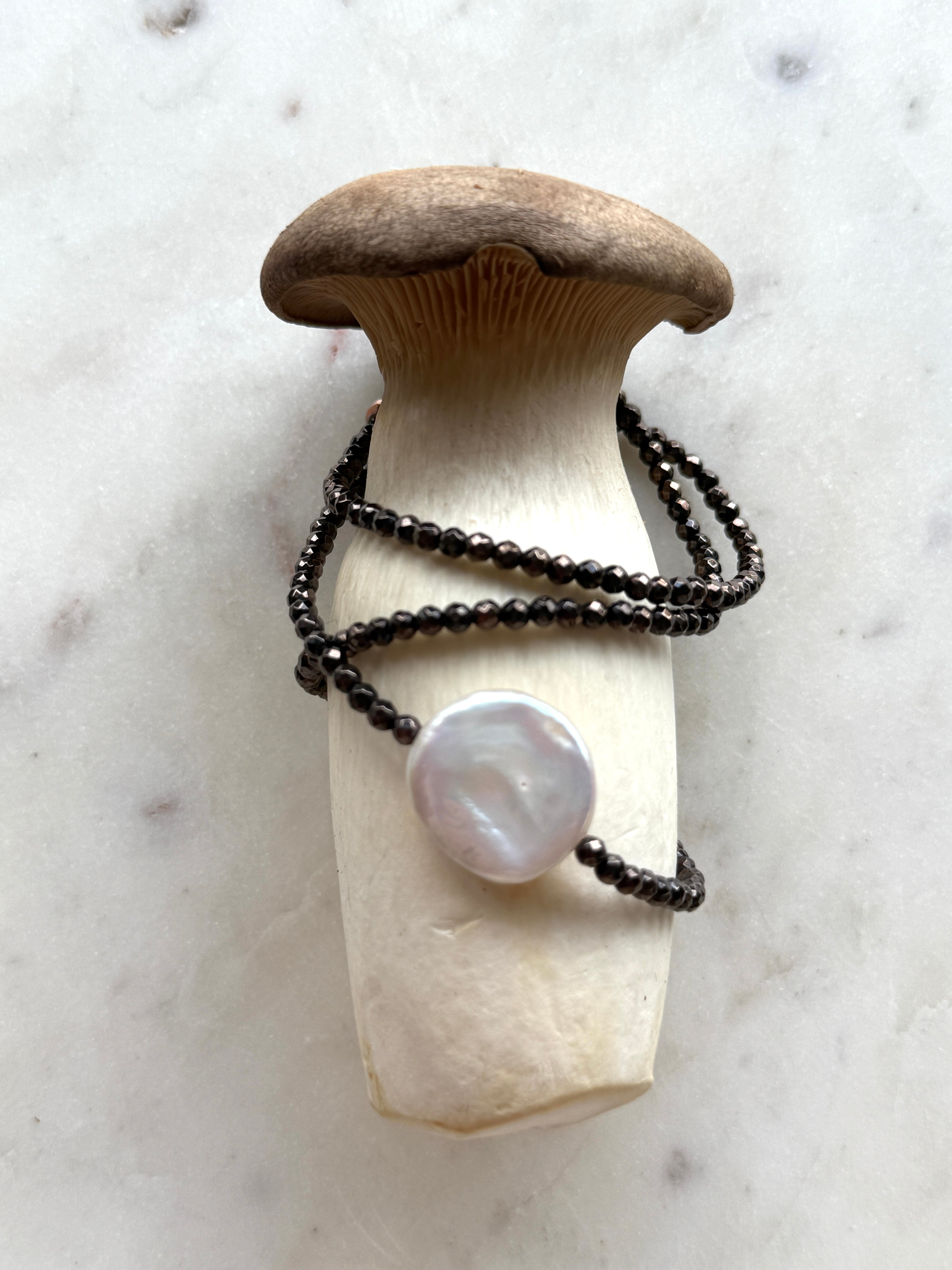 Dunkelbraune Hämatite und eine weiße, flache Süßwasserperle